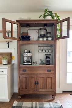 a wooden cabinet filled with dishes and cups on top of a rug in a kitchen