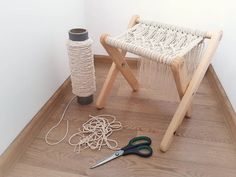 a pair of scissors sitting on top of a wooden floor next to a rope covered stool