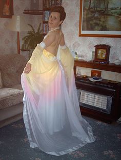 a woman in a yellow and white dress posing for the camera with her back to the camera