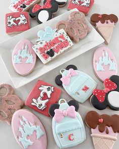 some decorated cookies are sitting on a plate with mickey mouse and minnie mouse cookie toppers