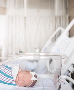 a newborn baby in a hospital bed with an iv machine behind it and the child's head is wrapped up