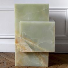 two square marble blocks sitting on top of a wooden floor in front of a white wall