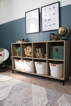 a living room with blue walls and white baskets on the shelf next to bookshelves