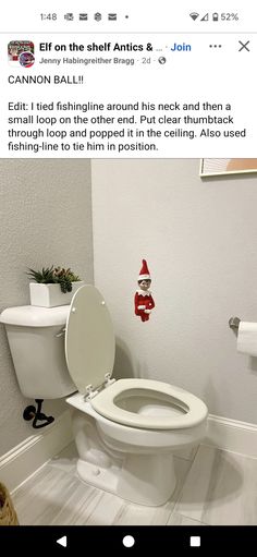 a white toilet sitting inside of a bathroom next to a roll of toilet paper on the floor