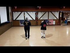 two people standing in an empty room with american flags on the wall and one person holding a baseball bat