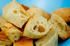 bread rolls piled on top of each other in a blue bowl, with one cut in half