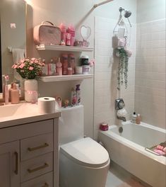 the bathroom is decorated with pink and white accessories, such as toilet paper rolls, soaps, and flowers