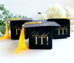 three graduation caps with tassels on them sitting next to white flowers and greenery