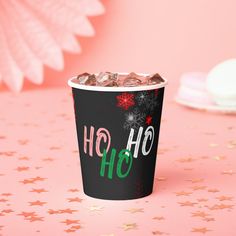 a black cup filled with chocolate and sprinkles on top of a pink table