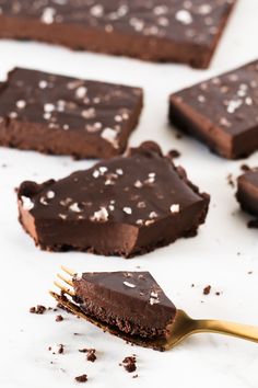 there are pieces of chocolate cake on the table with a gold fork next to it