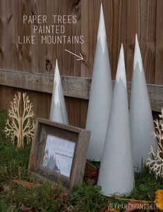 an image of some white cones on the ground with text above them that reads paper trees painted like mountains from her party pants