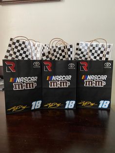 three bags with nascar logos on them sitting on a table in front of a wall