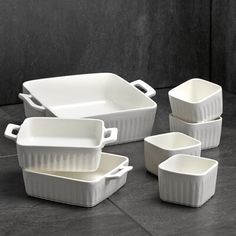 five white dishes and one bowl are sitting on the floor