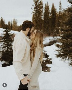 a man and woman are standing in the snow with their noses close to each other