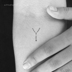 a small cross tattoo on the left side of someone's right arm and hand