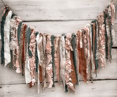 an assortment of scarves are hanging on a white wooden wall with planks in the background