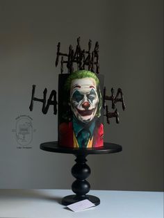 a birthday cake with the face of joker painted on it, sitting on top of a table