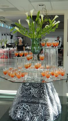 there are many glasses on the table with oranges in them, and some flowers