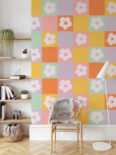 a chair sitting in front of a wall with flowers painted on it and bookshelves