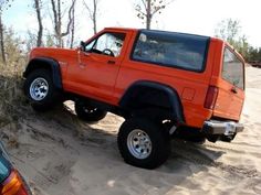 an orange pick up truck parked in the sand