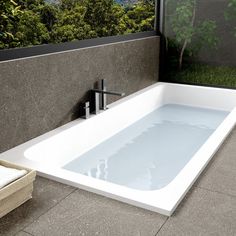 a white bath tub sitting next to a window with trees in the backround