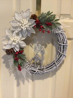 a christmas wreath with white flowers and silver antlers on the front door, next to a deer ornament