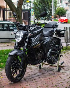 a black motorcycle parked on the side of a road next to a tree and grass