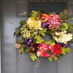 a wreath is hanging on the front door, decorated with flowers and greenery for an elegant touch