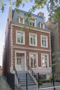 an old brick house with white windows and black iron railings on the front door