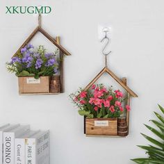 two wooden house shaped planters with flowers hanging on the wall next to each other