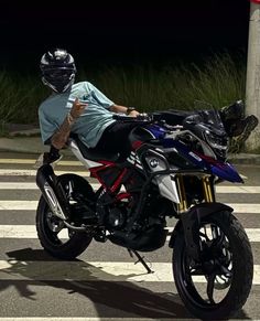 a man sitting on top of a motorcycle in the middle of the street at night