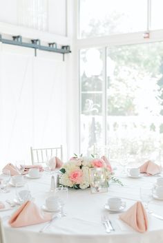 the table is set with white and pink napkins, silverware, and flowers