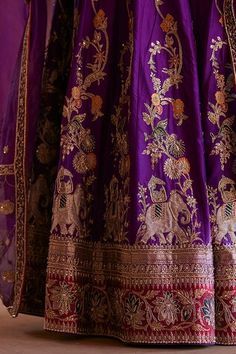 Purple flared katan silk banarasi kali lehenga with traditional elephant procession zardozi embroidery. Paired with an elbow sleeves V neck choli style padded blouse with intricate floral zardozi embroidery and organza dupatta adorned with hand embroidered zardozi borders. - Aza Fashions Purple Motif Sharara With Traditional Drape, Purple Sharara With Motifs In Traditional Drape, Purple Motifs Sharara With Traditional Drape, Purple Motifs Traditional Drape Sharara, Traditional Drape Purple Set With Motifs, Purple Sets With Motifs In Traditional Drape, Purple Sets With Traditional Motifs And Drape, Purple Silk Choli For Wedding, Purple Silk Lehenga For Wedding