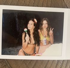 two women in bikinis posing for a photo with one holding up the peace sign