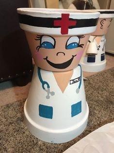 two medical themed pots sitting on top of a counter next to each other, one with a smiling face and the other with a stethoscope