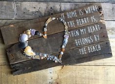 a heart made out of seashells on top of a wooden sign that says, if home is where the heart is, then my heart belongs by the beach