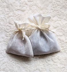 two small bags with white bows are sitting on a lace tablecloth