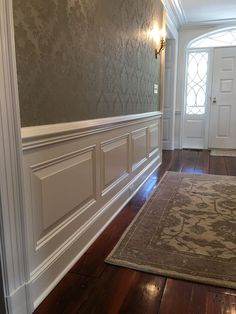 an empty room with wood floors and white trim on the walls, along with a rug