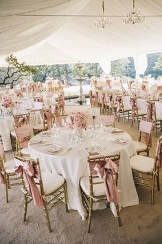 tables and chairs are set up for a wedding reception under a tent with chandeliers