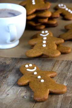 gingerbread cookies with white icing on a wooden table next to a cup of coffee