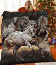 a woman holding up a blanket with horses on it in front of a christmas tree