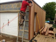 a man on a ladder working on a shed