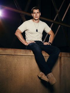 a man sitting on top of a wooden wall next to a light bulb in the dark