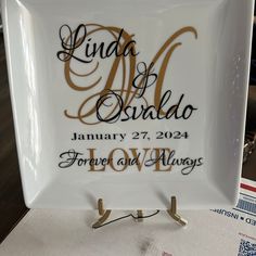 a white and gold plate with the names of two people on it, sitting on top of a table