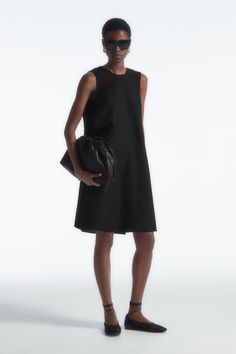 This simple mini dress rings true to the considered design ethos at COS. Offered in a perennial black hue, it's styled in a clean A-line silhouette and has an enthraling twist detail that frames the V-back. It is crafted from a TENCEL™ Lyocell and linen blend that's light in balmy weather. Relaxed fitSide seam pocketsTENCEL™ is a trademark of Lenzing AG. TENCEL™ Lyocell is made from renewable wood sources, using a process that recycles 99% of all chemicals and water  Shell: 77% TENCEL™ Lyocell, 23% Linen. Excluding trims / Machine wash Back length of size 6 is 95.3cm / Model wears a size 6 Simple Mini Dress, Glamorous Fashion, High Street Fashion, Dress Rings, Wool Dress, High Fashion Street Style, New Arrival Dress, Simple Dresses, Mini Black Dress