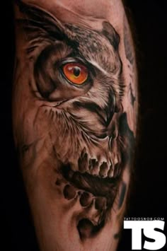 a man's arm with an owl and skull tattoo on it, which has orange eyes