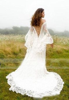 a woman in a white dress is standing on the grass with her back to the camera