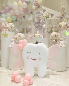 a white tooth with pink and yellow balloons in the background