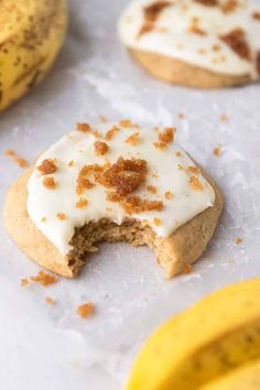 a cookie with white frosting and cinnamon sprinkles next to some bananas