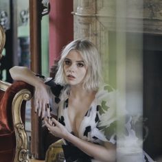 a woman sitting on top of a red chair next to a mirror